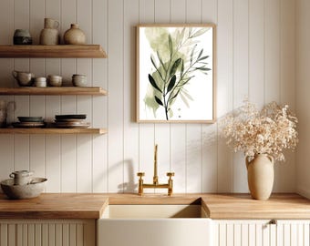 Puede incluir: Una impresión botánica enmarcada con ilustraciones de hojas verdes y negras sobre un fondo blanco. La obra de arte se muestra en un marco de madera clara, agregando un toque de decoración inspirada en la naturaleza a un entorno de cocina. La cocina tiene estantes de madera y un fregadero blanco.