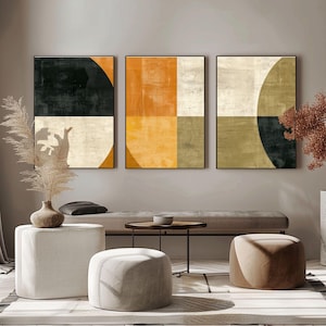 Puede incluir: Tres obras de arte abstractas enmarcadas con formas geométricas en tonos negro, naranja y beige. La obra de arte se exhibe sobre un banco con otomanas de color neutro y una pequeña mesa redonda, creando un diseño interior moderno.