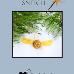 May include: A handmade felt Snitch ornament with yellow wings and a gold sequined body. The ornament is set against a snowy background with pine branches and the text "SNITCH". The Bird Brain Feltworks logo is at the bottom.