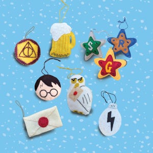 May include: A collection of handmade felt ornaments in various shapes and colors. Includes a yellow beer mug, stars with letters, a round Harry Potter face, an owl with a letter, an envelope, a lightning bolt, and a Deathly Hallows symbol.