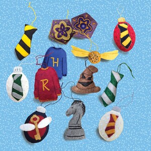 May include: A collection of felt ornaments in various shapes and colors. Includes a yellow and black striped tie, a red and gold tie, a blue sweater with a gold "H", a red sweater with a gold "R", and a brown sorting hat.