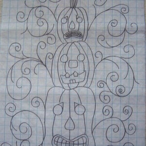 May include: A hand-drawn sketch of a Halloween-themed design featuring three stacked jack-o'-lanterns with various facial expressions. The design includes swirling vines and is drawn on graph paper.