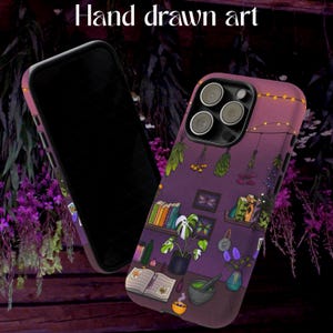 Op de afbeelding: Twee telefoonhoesjes met een paarse en roze gradiënt. De hoesjes hebben een handgetekende illustratie van een hekseninterieur met boeken, planten en hangende kruiden. De tekst "Hand drawn art" staat bovenaan.