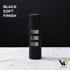 K&ouml;nnte beinhalten: Ein schwarzer Becher mit weichem Finish und dem Text "YOUR LOGO HERE" in Silber. Der Becher ist zylindrisch mit einem schwarzen Deckel. Die Worte "BLACK SOFT FINISH" stehen oben links. Der Hintergrund ist schwarz und die Oberfl&auml;che ist wei&szlig;er Marmor.