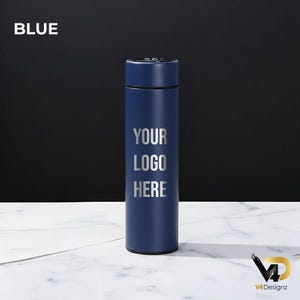 K&ouml;nnte beinhalten: Eine marineblaue, isolierte Wasserflasche mit dem Text "YOUR LOGO HERE" in Silber. Das Wort "BLUE" befindet sich in der oberen linken Ecke. Die Flasche ist zylindrisch und steht auf einer wei&szlig;en Marmoroberfl&auml;che vor einem schwarzen Hintergrund.