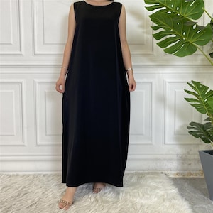 May include: A sleeveless, floor-length black dress. The dress has a simple, round neckline and a loose, flowing silhouette. The fabric appears to be a soft, solid material. The dress is suitable for casual or semi-formal occasions.