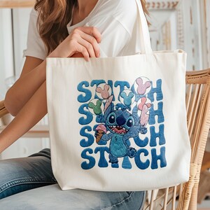 May include: Cream-colored tote bag featuring a blue cartoon character holding ice cream and balloons, with the word "Stitch" in blue block letters. The bag is made of a sturdy fabric and has a simple design.