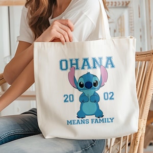 May include: Cream-colored tote bag featuring a blue cartoon character with large ears and the text "OHANA MEANS FAMILY". The character is in the center, with the numbers "20" and "02" on either side.