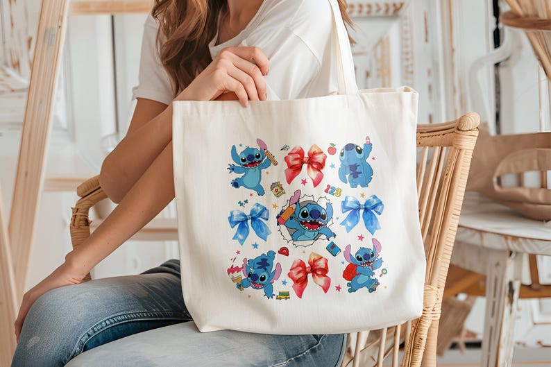 Op de afbeelding: Een witte canvas draagtas met een kleurrijke grafische print van het blauwe personage Stitch in verschillende houdingen, afgewisseld met rode en blauwe strikken, kleine sterretjes, een rode appel, een gele schoolbus en de cijfers 123.