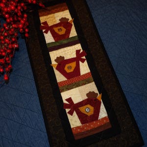 May include: A white ceramic mug with a black handle and the text "But First, Coffee" in a black, handwritten-style font. The mug is on a white surface.