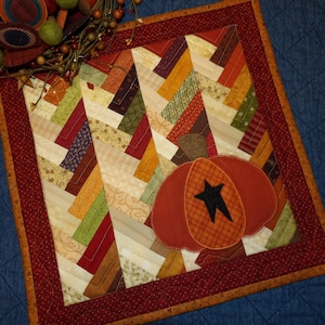 May include: A quilted table runner with a patchwork design featuring a variety of fall colors, including red, orange, yellow, and brown. The runner features a large, orange pumpkin with a black star in the center.