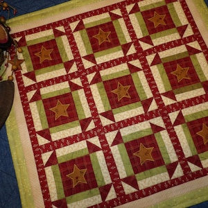 May include: A red and green patchwork quilt with a star pattern. The quilt is made of different fabrics and has a rustic, country feel.