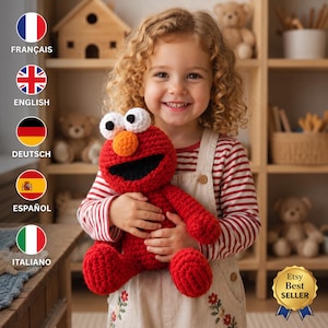 May include: A bright red crocheted plush toy featuring a large round head, a prominent orange nose, two white eyes with black pupils, and a wide black mouth, held by a child wearing a red and white striped long-sleeve shirt and beige overalls.