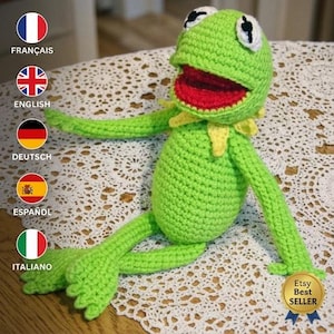 May include: A handmade crochet frog doll in bright lime green yarn with a red mouth, white eyes with black pupils, and a yellow collar. The doll features long, thin arms and legs with webbed feet. A gold badge with the text Etsy Best Seller is visible.