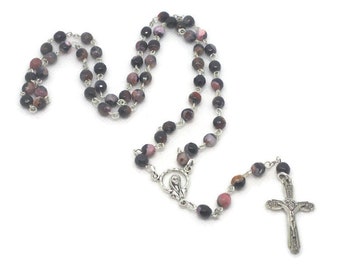 May include: A black and pink agate rosary with a silver crucifix and a silver charm of the Virgin Mary.