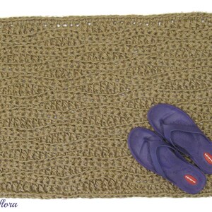 May include: A brown woven jute rug with a textured pattern. Two purple flip-flops with red logos are on top of the rug.