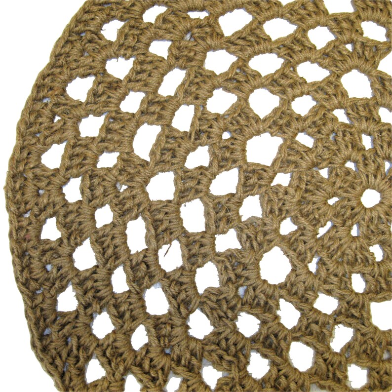 May include: A brown crocheted round rug with a circular pattern of holes. The rug is made of natural fibers and has a rustic look.