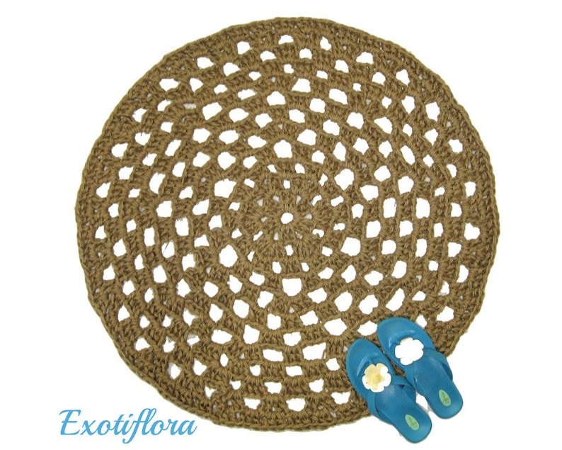 May include: A round, brown, crocheted jute rug with a circular pattern. The rug is made of natural fibers and has a rustic, bohemian style.