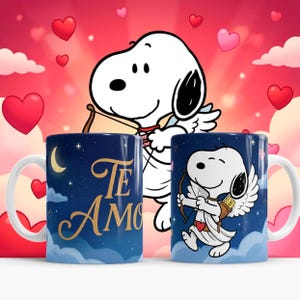 May include: Two ceramic mugs with a Snoopy design. One mug has the words "Te Amo" in gold lettering against a dark blue starry sky background. The other mug features Snoopy as Cupid with a bow and arrow, set against a similar background.