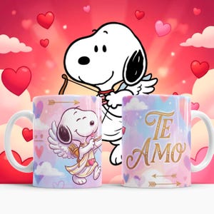 May include: Two white ceramic mugs with Snoopy-themed designs. One mug features Snoopy as Cupid with a bow and arrow, the other has the words "Te Amo" in gold lettering. The mugs have a pink and blue watercolor background with hearts.