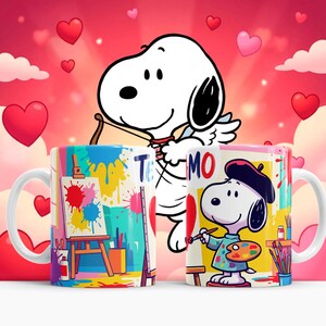 May include: Two white ceramic mugs featuring Snoopy illustrations. One mug shows Snoopy as an artist with a beret and palette, the other shows an art easel with paint splatters. The background is pink with hearts.
