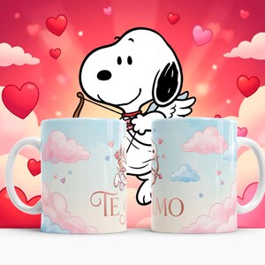 May include: Two white ceramic mugs with a light blue and pink cloud design, featuring Snoopy as Cupid with a bow and arrow. The mugs have the text "Te Amo" in a cursive font. Hearts float in the background.