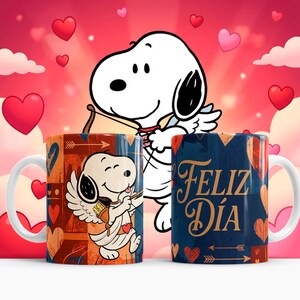May include: Two ceramic mugs featuring Snoopy as Cupid with a bow and arrow, set against a pink and red heart-filled background. One mug has the text "Feliz D&iacute;a" in gold. The mugs have white handles and are decorated with hearts and arrows.