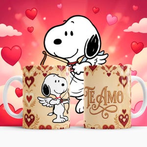 May include: Two white ceramic mugs with a Snoopy design. One mug features Snoopy as Cupid with a bow and arrow, the other mug has the words "Te Amo". The mugs have a cream background with red hearts and decorative elements.