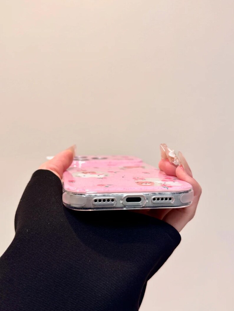 Pu&ograve; includere: Custodia per telefono rosa con bordo trasparente. La custodia presenta un motivo ripetuto di personaggi dei cartoni animati e fiori. La custodia &egrave; realizzata in un materiale trasparente e flessibile.