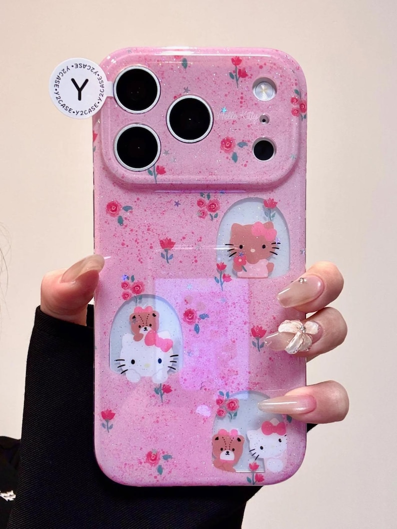Pu&ograve; includere: Custodia per telefono rosa con finitura glitterata, con motivo floreale e disegni di Hello Kitty. La custodia ha ritagli per la fotocamera e il flash e include il testo "Y2CASE".