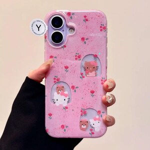Pu&ograve; includere: Custodia per telefono rosa con motivo floreale e glitter. La custodia presenta tre finestre ritagliate con disegni di Hello Kitty e orsi. La custodia ha un adesivo Y2CASE.