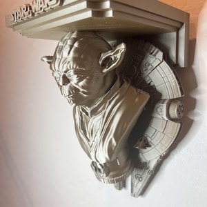 Puede incluir: Una estantería de Yoda de Star Wars de color plateado. La estantería presenta el logotipo de Star Wars y un busto detallado de Yoda. El diseño de la estantería incorpora elementos del Halcón Milenario, añadiendo un toque único a este coleccionable.