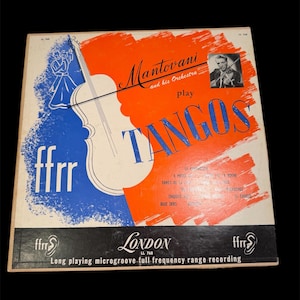 May include: Vintage vinyl record album cover for "Mantovani and his Orchestra Play Tangos." The cover features a white violin graphic, blue and orange paint strokes, and the word "TANGOS" in large blue letters.