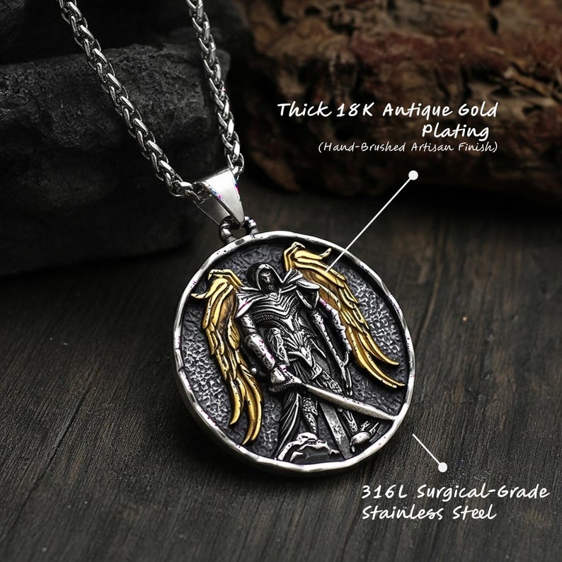 Textured st michael pendant resting on dark surface, antique silver catholic jewelry with contrasting gold plated wings and bold christian necklace design.
