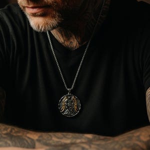 St michael pendant worn by man on wheat chain, masculine christian necklace styled with dark shirt, meaningful armor of god symbol and powerful christian jewelry gift for him.