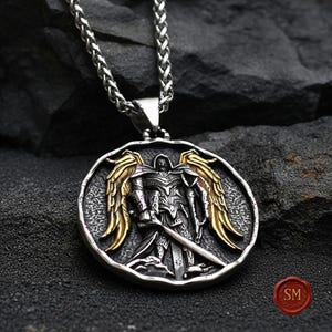 Round st michael necklace placed on black stone backdrop, antique style catholic jewelry medallion featuring gold wings and detailed sword engraving.
