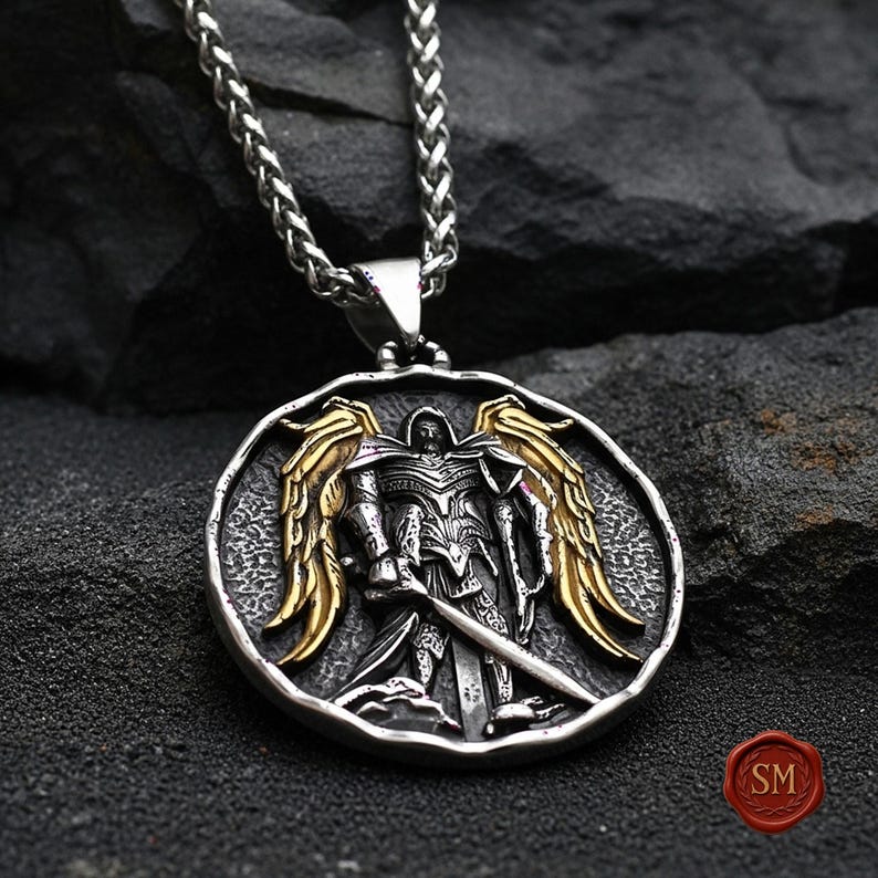 Round st michael necklace placed on black stone backdrop, antique style catholic jewelry medallion featuring gold wings and detailed sword engraving.