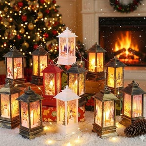 Pode incluir: Uma coleção de lanternas decorativas de Natal com luzes quentes e convidativas. As lanternas apresentam cenas de inverno com árvores, bonecos de neve e veados. As lanternas são em várias cores, incluindo vermelho, branco e dourado.
