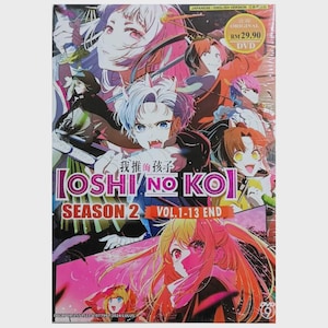Może przedstawiać: Zestaw DVD z ilustracjami w stylu anime. Widoczny jest tytuł "OSHI NO KO", a także "SEASON 2" i "VOL.1-13 END." Okładka przedstawia kilka postaci z anime o jasnych włosach i dynamicznych pozach. Widoczny jest również tekst "JAPANESE / ENGLISH VERSION".