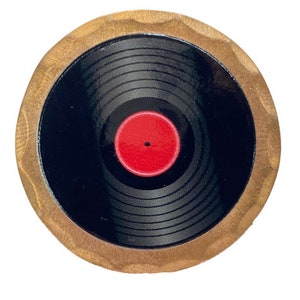 May include: A round wooden coaster with a black and red vinyl record design. The record has a red label in the center.