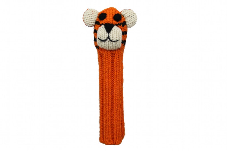 May include: Orange and black knitted golf club head cover with a tiger face. The tiger has white ears, a white nose, and black eyes.