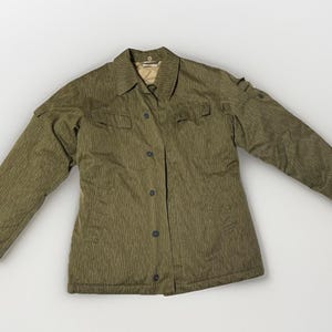 May include: Olive green military-style jacket with a vertical striped pattern. The jacket has a collared neckline, button-down front, and two chest pockets. The long sleeves have buttoned cuffs. The jacket is made of a durable fabric.