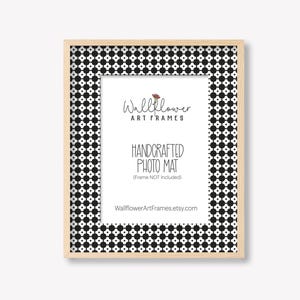 May include: A rectangular photo frame with a black and white patterned border and a natural wood-colored frame. The center features a white mat with text that reads "Wallflower Art Frames" and "Handcrafted Photo Mat."