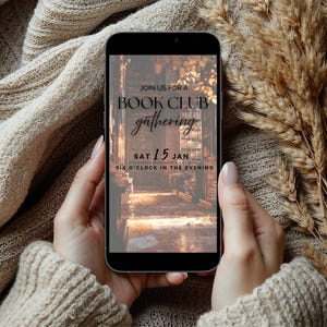 May include: A smartphone displays a book club gathering invitation. The screen shows text: "Join us for a Book Club gathering, Sat 15 Jan, Six o'clock in the evening." The phone is held by hands, against a backdrop of a beige sweater and dried wheat.