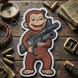 May include: Embroidered patch featuring a cartoon monkey holding a rifle. The patch is brown, tan, and black with a white border. The monkey is smiling. The patch is on a wooden surface with other military-themed items.