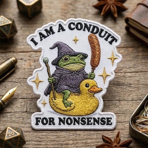 May include: Embroidered patch featuring a frog in a wizard hat and cloak riding a yellow duck. The patch reads "I AM A CONDUIT FOR NONSENSE" in white lettering. The frog holds a staff and a corn dog.