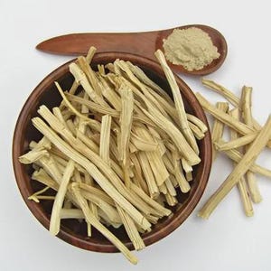 May include: A wooden bowl filled with light-colored, dried plant stems. A wooden spoon holds a pile of light brown powder. The items are on a white surface. The bowl and spoon are made of dark brown wood.