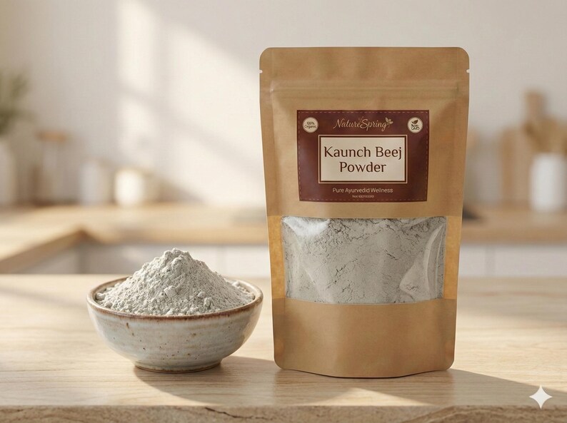 May include: A package of Kaunch Beej Powder from Nature Spring, with a clear window showing the powder. A small bowl of the powder sits next to the package. The powder is a light grey color.