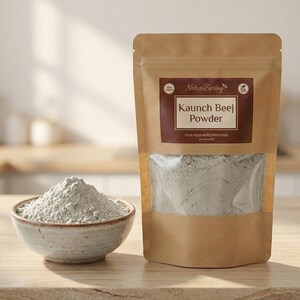 May include: A package of Kaunch Beej Powder from Nature Spring, with a clear window showing the powder inside. A small bowl of the powder sits next to the package. The powder is a light grey color.