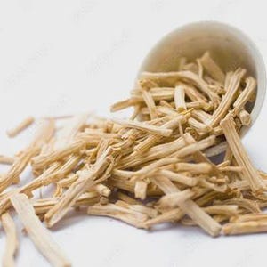 May include: A light beige ceramic bowl tipped over, spilling out numerous dried, light brown, stick-like pieces. The pieces are scattered on a white surface, creating a natural, earthy aesthetic. The image is well-lit, highlighting the texture of the items.